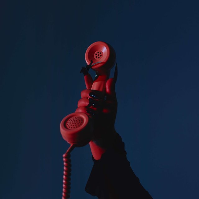 Pochette de 911 : une main tient un combiné de téléphone rouge sur fond bleu nuit