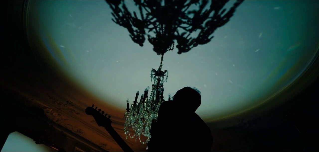 Une scène du clip de Dangerous Woman : une silhouette avec une guitare sous un lustre